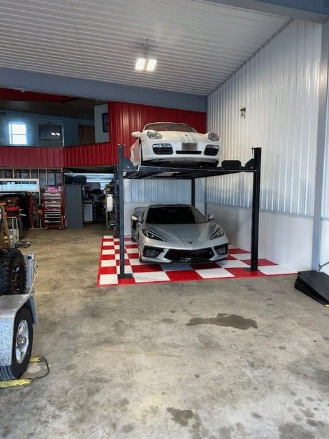 Sports Vehicles on car lift over a red and white tile pad.